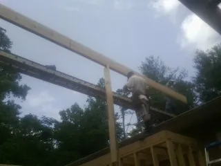 Carpenter setting a ridge beam over a new addition frame — Ice Dam Removal by Roofing Brothers in Vona
