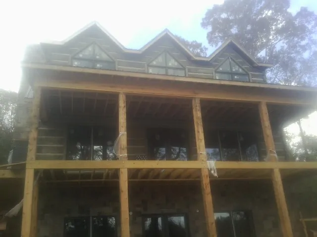 Dormers and porch framing on a large log home under construction — Roof Coating work by our crew in Vona