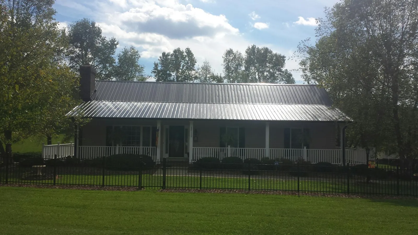 Gray metal roof on a brick ranch with a full width front porch — Gutter Guard Installation work by our crew in Vona