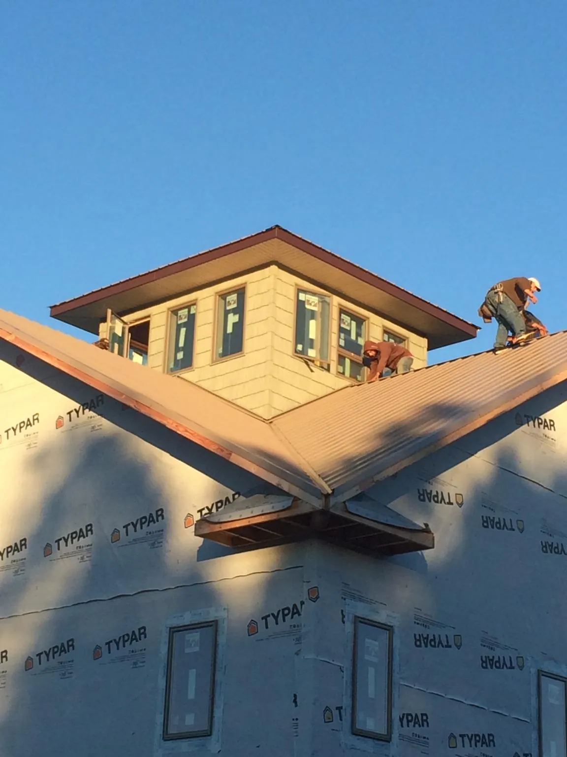 Roofers working around a rooftop cupola on a new metal roof at sunset — Roof Waterproofing in Vona by Roofing Brothers